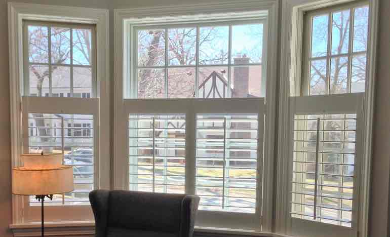 Bottom half white shutters in den bay window.